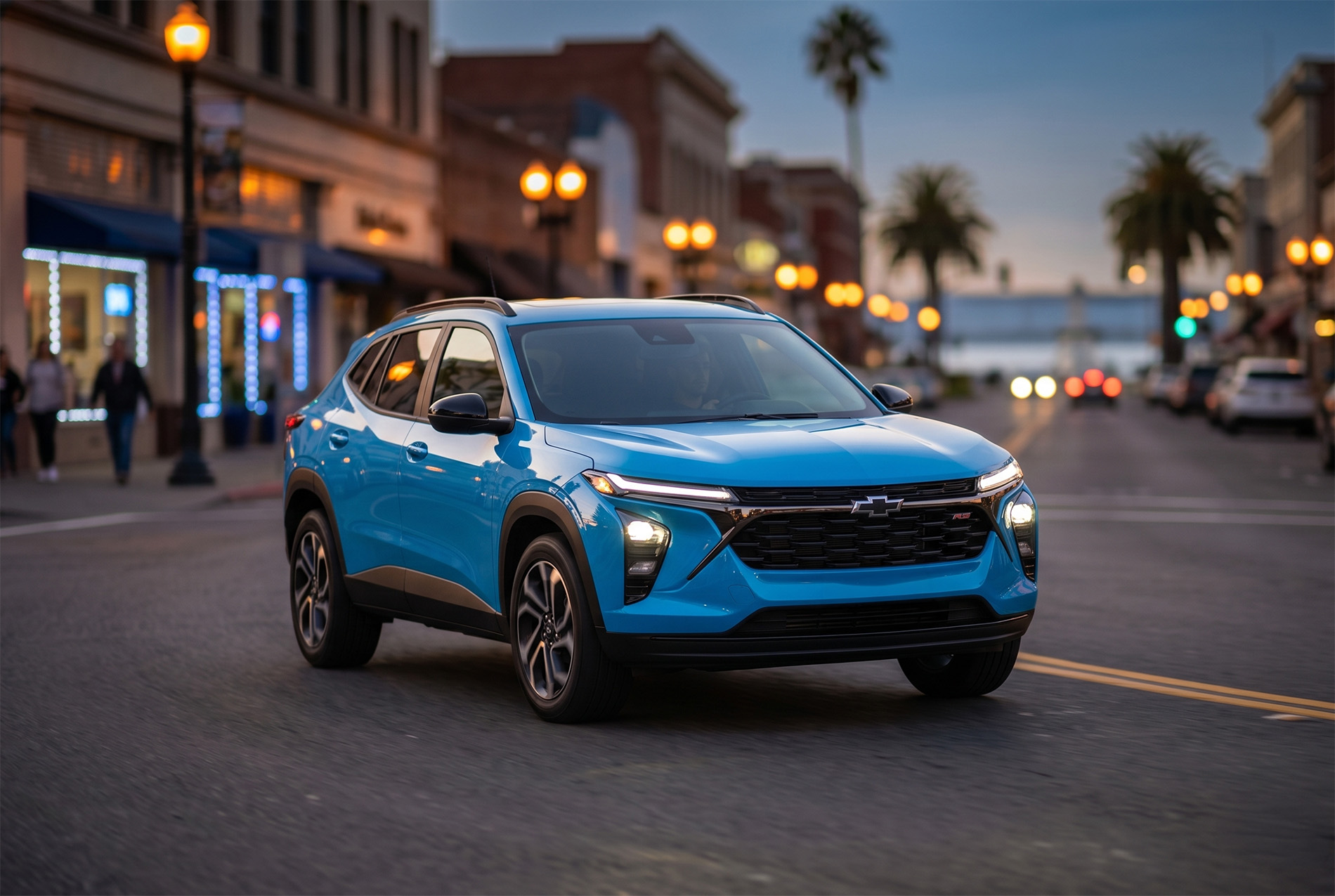 A blue 2026 Chevrolet Trax driving through downtown Pittsburg California at night