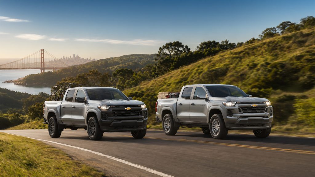 Two silver 2026 Chevrolet Colorado pickup trucks drive side by side along a coastal highway overlooking the Golden Gate Bridge and San Francisco Bay, one carrying bicycles and the other loaded with gear, illustrating the truck’s versatility and trim options available at Delta Chevrolet in Pittsburg, CA.