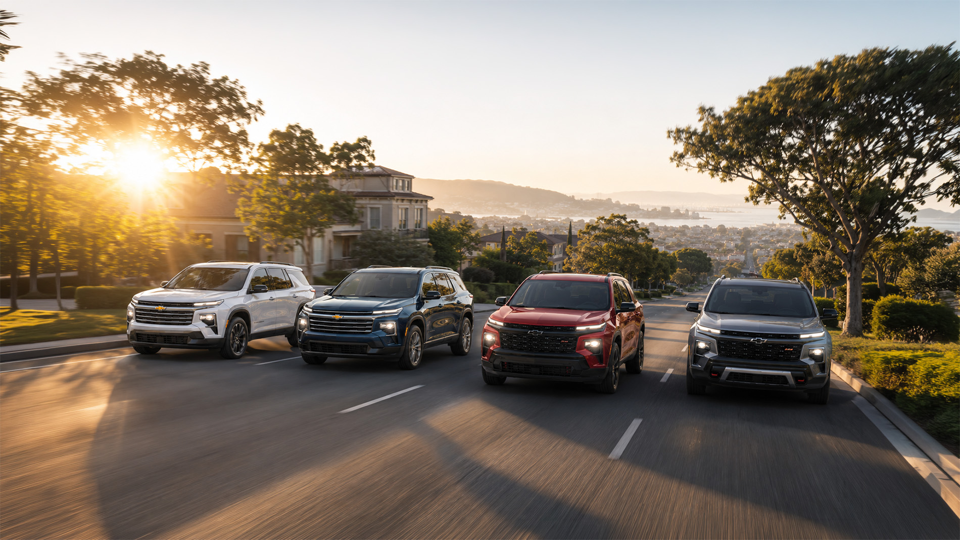 Four 2026 Chevrolet Traverse SUVs in white, blue, red, and gray parked side by side in a residential driveway at sunset, highlighting the range of Traverse trim levels available at Delta Chevrolet in Pittsburg, CA.